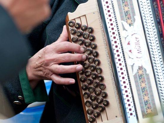Hand spielt Knöpfe auf einem traditionellen diatonischen Akkordeon mit Verzierung